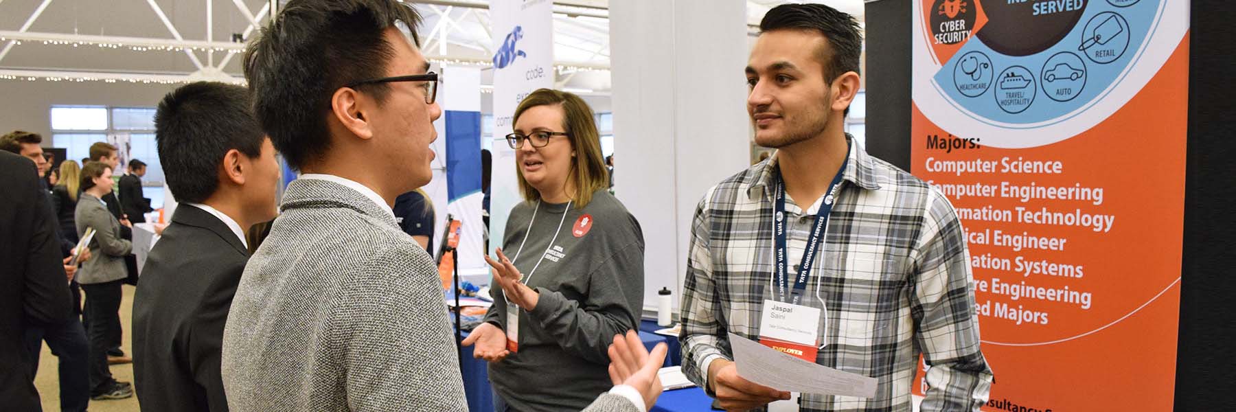 Professionally dressed students talk with representatives at a career fair.