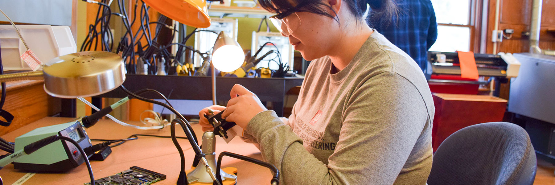 A student working in Makerspace lab with a soldering iron.