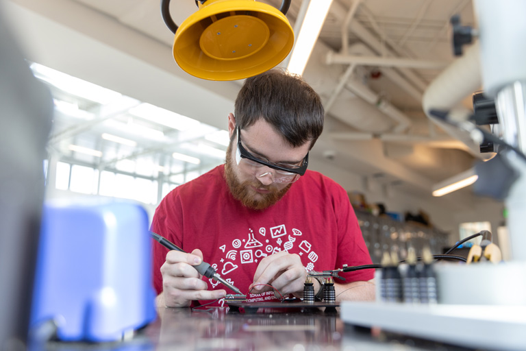 Student in a lab working on a circuit board